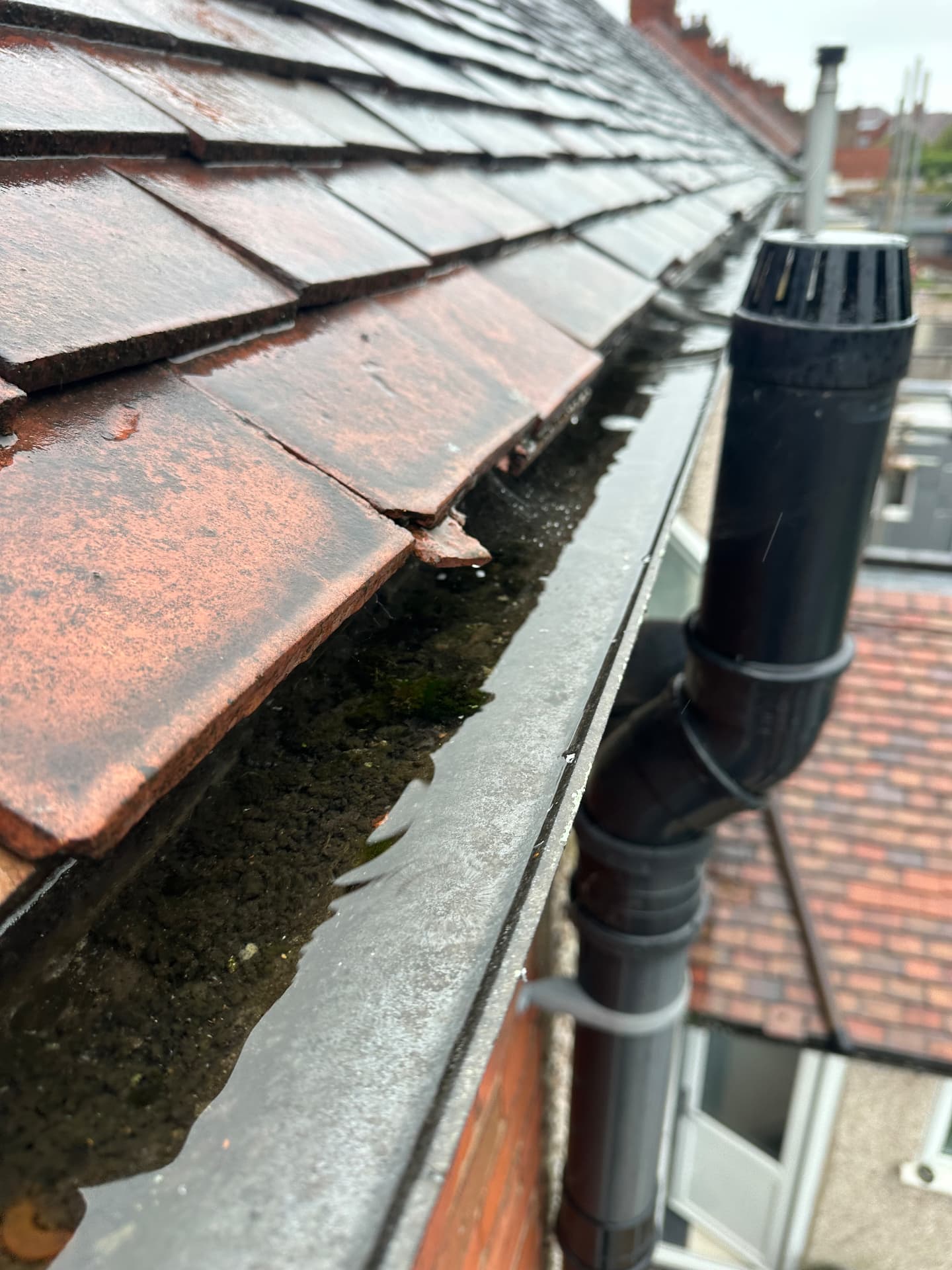 Blocked gutter before gutter cleaning in Coventry, moss and grit washed off the tiles